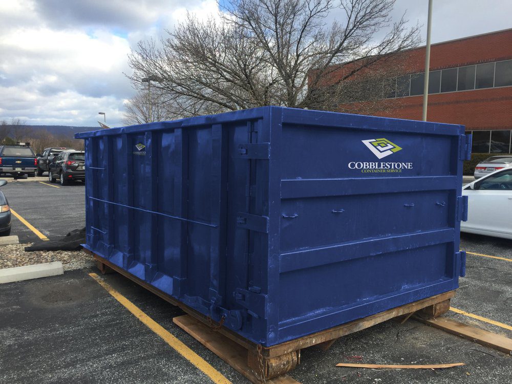 a blue roll-off dumpster sits in a parking lot.