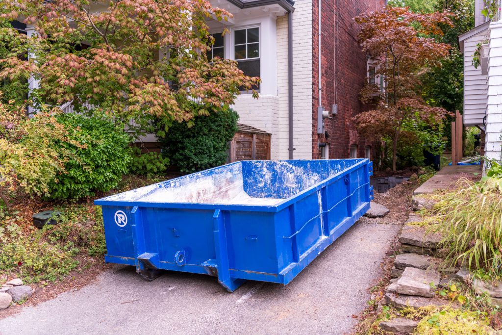 A small roll-off dumpster in a suburban driveway