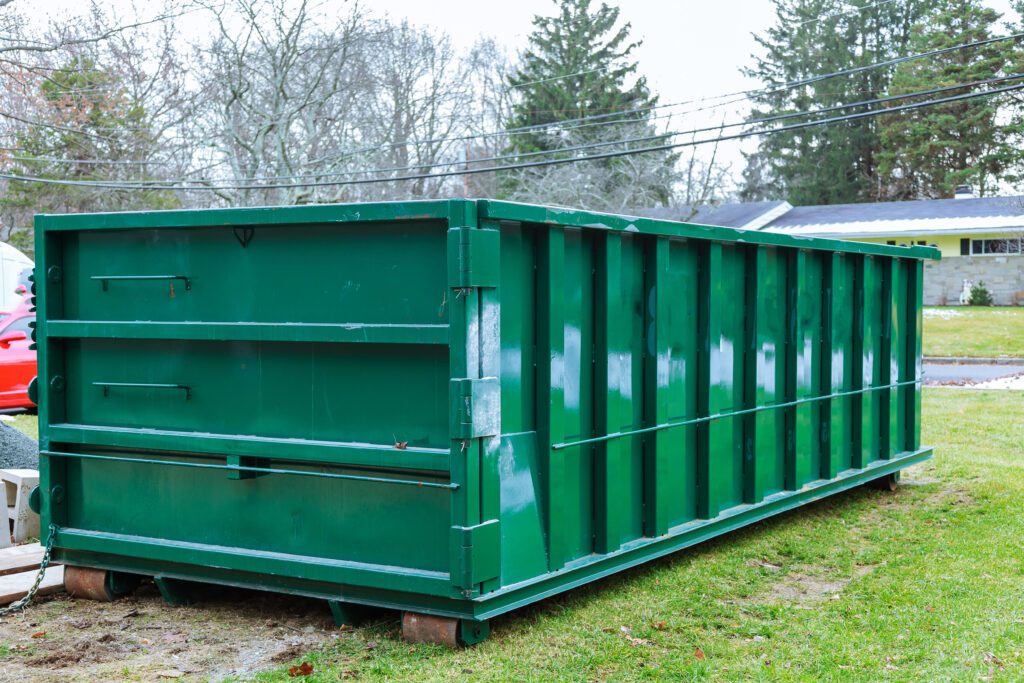 Green dumpster on a lawn.